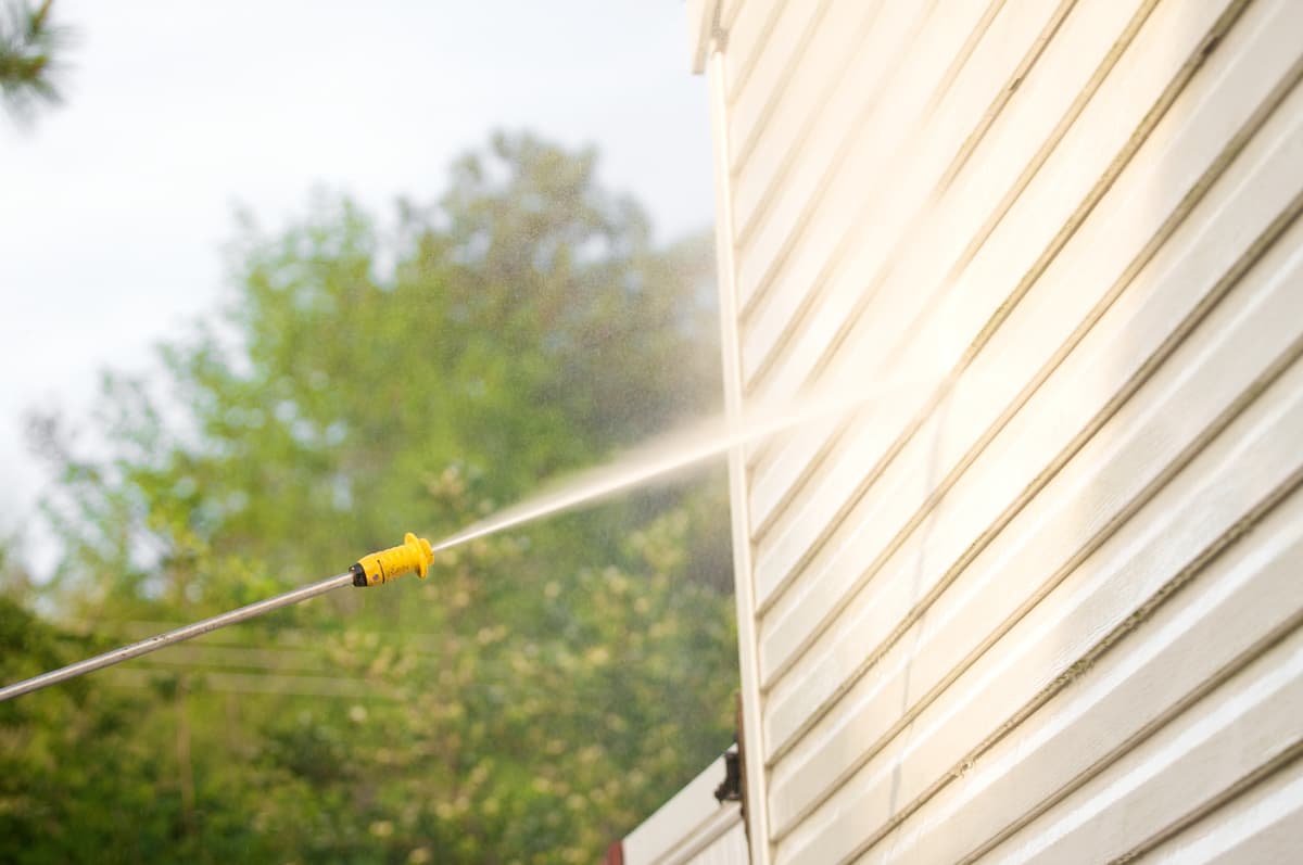 Pressure washer spraying and cleaning house siding